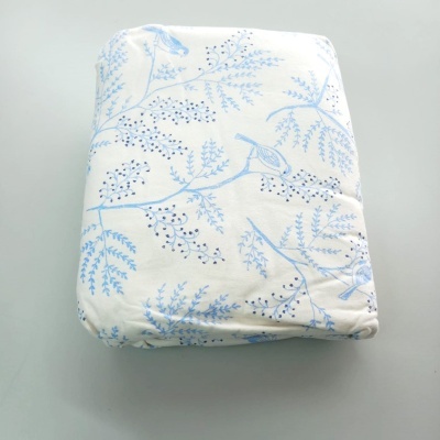 Capa de tecido branco com padrão azul de ramos e pássaros