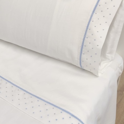 Conjunto de cama branco com bordado azul e padrão de pontos azuis