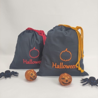 Bolsas cinza escuras com cordões coloridos e decoração Halloween com abóboras e aranhas pequenas