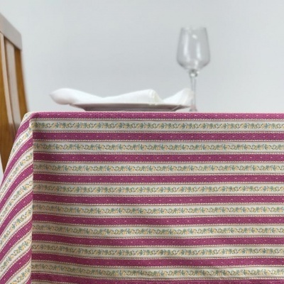 Toalha de mesa listrada com padrão floral em mesa com cadeira, copo de vidro e guardanapo branco