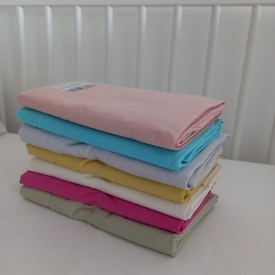 Pilha de tecidos coloridos dobrados sobre superfície branca com cabeceira