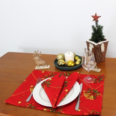 Conjunto de mesa natalício com prato branco, guardanapo vermelho, talheres, copo de vidro, decorações de rena dourada, pinheiro artificial e velas com bolas douradas.