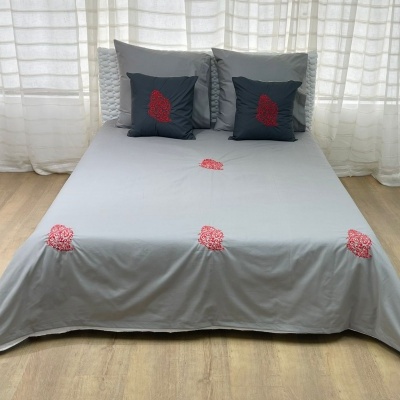 Cama com jogo de cama cinzento com bordados vermelhos flores e almofadas
