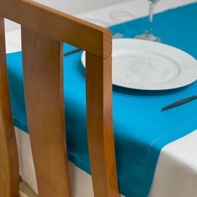 Cadeira de madeira e mesa posta com toalha branca e passadeira azul