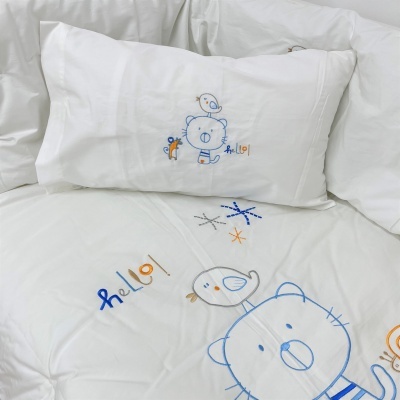Roupa de cama branca com desenhos bordados de urso e pássaro e texto 'hello!'