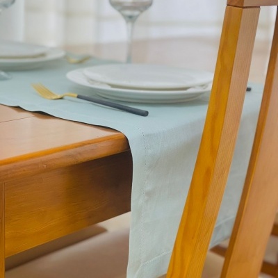 Mesa de madeira com toalha azul clara e louça branca arrumada