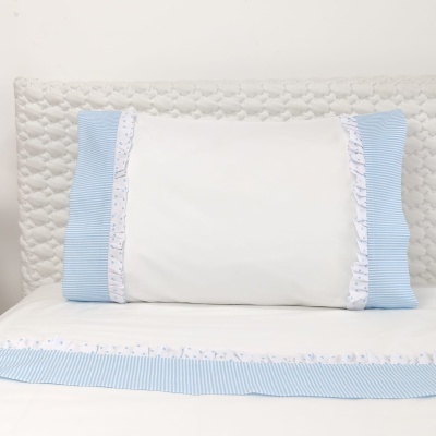 Fronha branca com laterais azuis e renda em cama com colchão almofadado branco