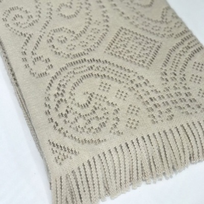 Tapete ou manta bege com padrão geométrico embutido e franjas