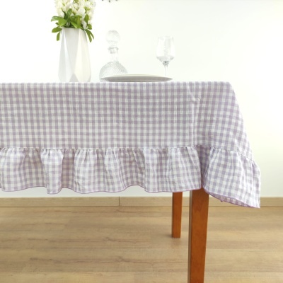 toalha de mesa xadrez lilás com branco e babado sobre mesa de madeira