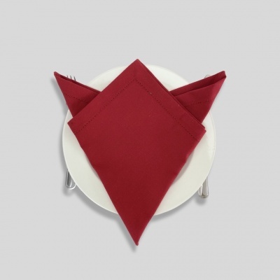 Guardanapo vermelho no prato branco com talheres ao lado