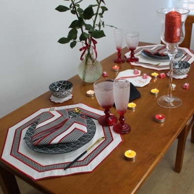 Mesa de madeira posta para refeição com pratos, talheres, copos e decoração