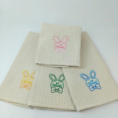 Quatro toalhas bege claro com bordados coloridos de coelhos