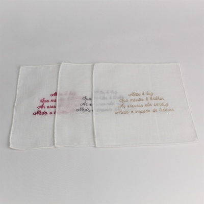 Três toalhas brancas com bordados coloridos dispostas lado a lado