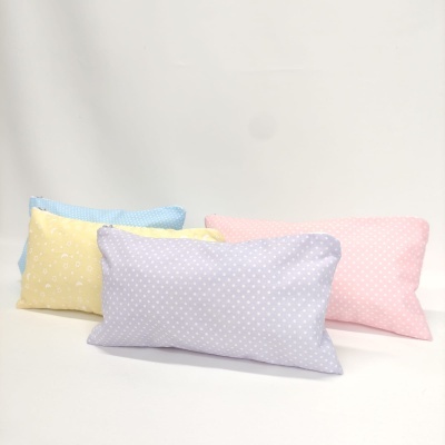 Quatro almofadas retangulares em cores pastel com padrões de flores e bolinhas