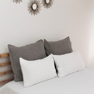 Almofadas decorativas cinzentas e brancas em cama com cabeceira de madeira