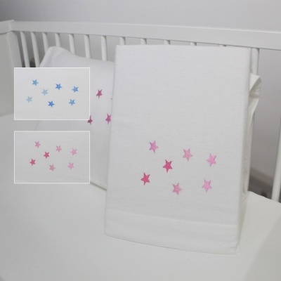 Toalha branca com estrelas cor-de-rosa e lilás dentro de um berço branco