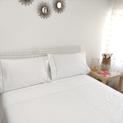 Jogo de cama branco com fronhas e lençol em quarto com decoração minimalista