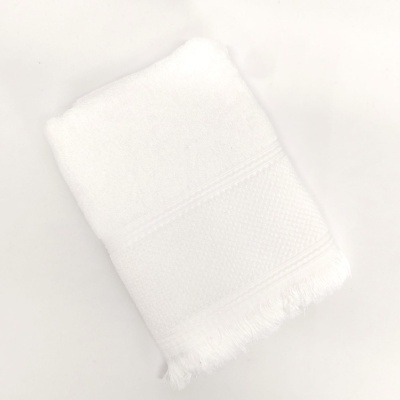 Toalha branca dobrada com franjas sobre fundo branco