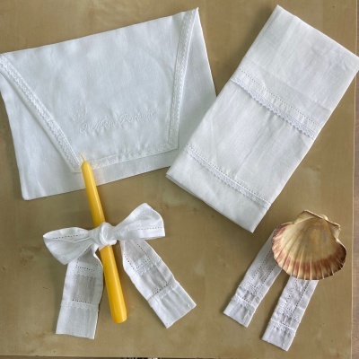 tecidos brancos bordados, vela amarela com fita rendada, concha natural