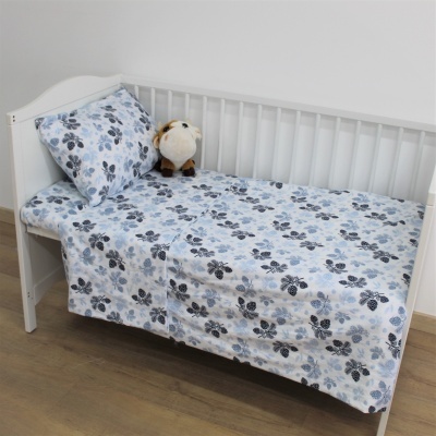 Cama de bebé branca com roupa de cama estampada e peluche castanho.