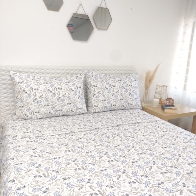 Jogo de lençóis floral azul e cinza em cama branca com mesas de cabeceira e espelhos hexagonais