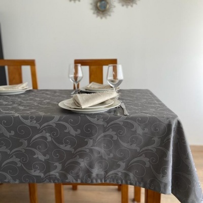 Mesa posta com toalha cinzenta com padrão floral e duas taças numa sala minimalista