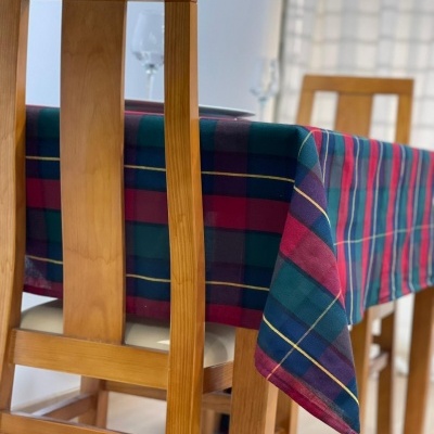 Toalha de mesa xadrez em mesa de madeira com cadeiras, interior com cortinas e copo de vidro