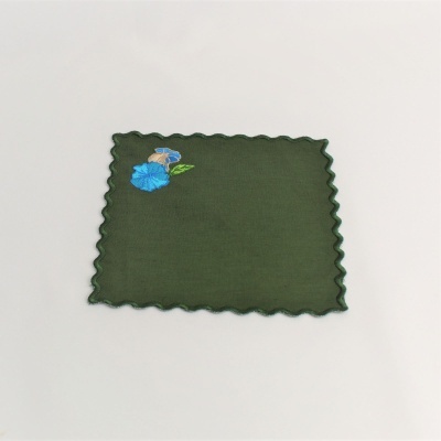 Pano verde com borda ondulada e bordado de flor azul