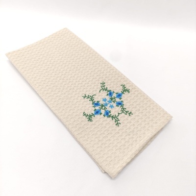 Toalha bege com bordado azul e verde