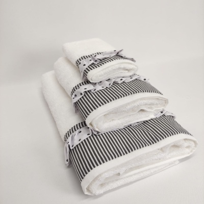 Toalhas brancas com faixas cinza com riscas pretas e bordas com bolinhas azuis empilhadas