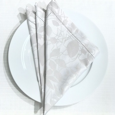 Guardanapo de tecido branco com padrão floral em relevo sobre prato branco