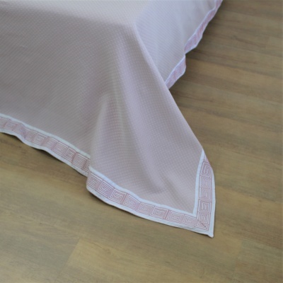 Cobertura de cama branca com borda rosa decorativa e chão de madeira clara