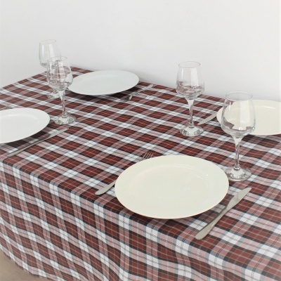 Mesa posta com toalha xadrez vermelha, branca e cinza, pratos brancos, taças de vidro e talheres de metal