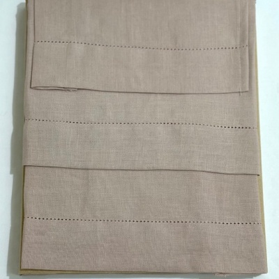 Conjunto de roupa de cama bege com padrão de linhas perfuradas.