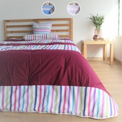 Cobertor de cama bordeaux com riscas coloridas numa cama de madeira