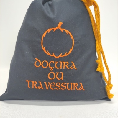 Saco de pano cinzento com cordão amarelo e texto laranja com abóbora