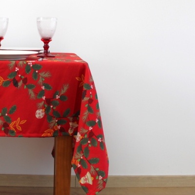 Toalha de mesa vermelha com padrão festivo sobre mesa de madeira com duas taças