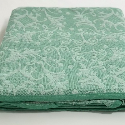 toalha de mesa verde claro com padrão floral creme dobrada