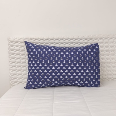 Travesseiro azul com âncoras brancas sobre cama branca