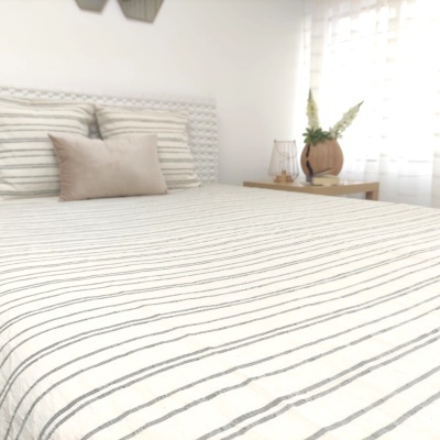 lençol de cama branco com riscas finas cinzentas e almofadas numa cama