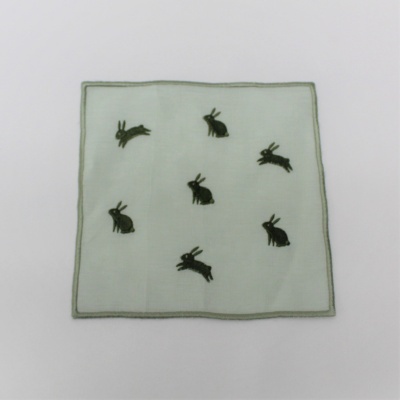 Pano branco quadrado com borda cinza e bordados de coelhos pretos.