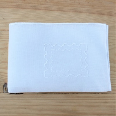 Guardanapo branco com bordado em relevo sobre madeira clara