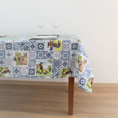 Toalha de mesa azul e branca com ilustrações e texto, sobre mesa de madeira clara