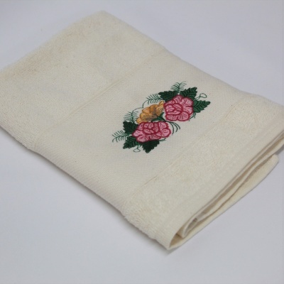 Toalha creme com bordado floral colorido dobrada