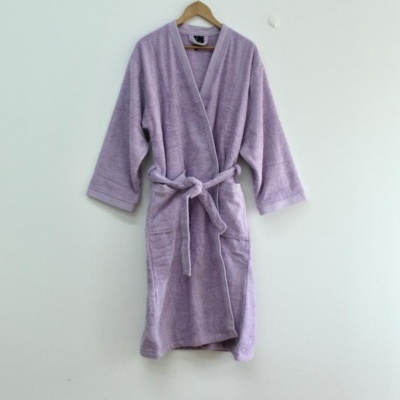 Robe de banho lilás pendurado num cabide contra parede branca