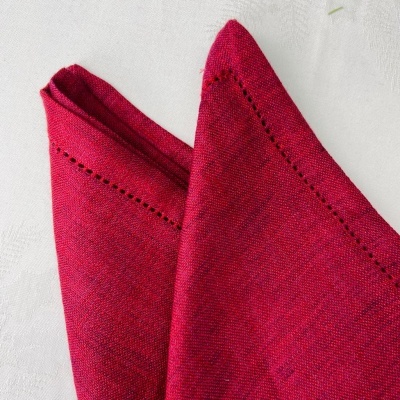 Guardanapo vermelho com padrão de buracos na borda sobre superfície branca