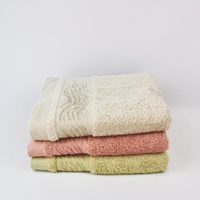 Três toalhas de banho empilhadas em creme, coral e verde