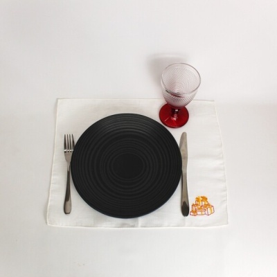 Conjunto de jantar com prato preto, talheres, copo e toalhete bordado