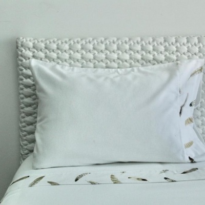 Travesseiro branco em cama branca com cabeceira trançada