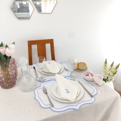 Mesa posta com pratos e copos, decorada com flores em vasos e toalha bege